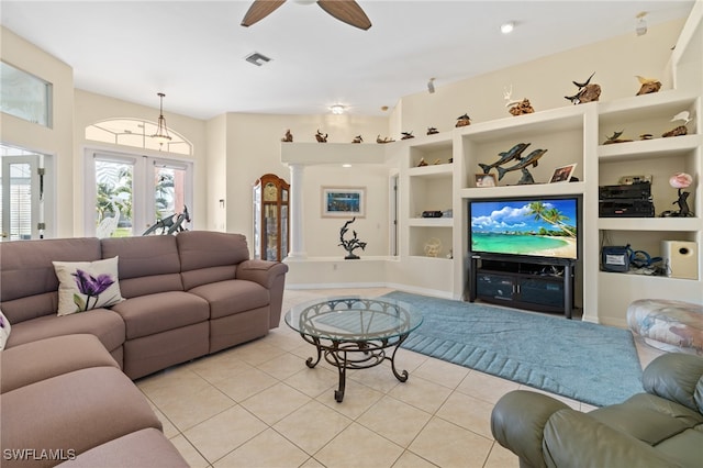 living room featuring built in shelves, light tile patterned floors, ceiling fan, and ornate columns