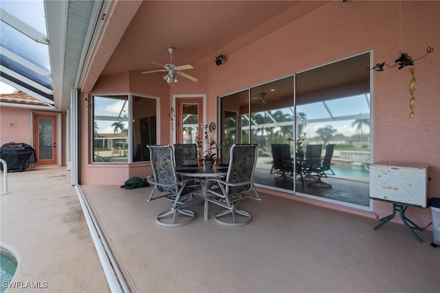 view of patio with ceiling fan and glass enclosure