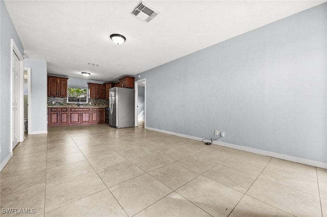 kitchen with light tile patterned floors, backsplash, and stainless steel refrigerator