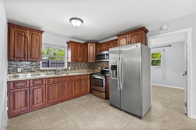 kitchen featuring light stone countertops, appliances with stainless steel finishes, backsplash, and sink