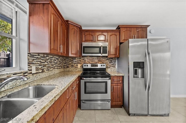 kitchen featuring sink, decorative backsplash, light tile patterned flooring, light stone counters, and stainless steel appliances