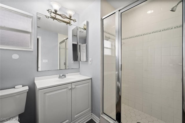 bathroom with vanity, a shower with shower door, and toilet