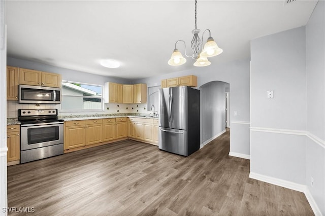 kitchen with light brown cabinets, sink, backsplash, decorative light fixtures, and appliances with stainless steel finishes