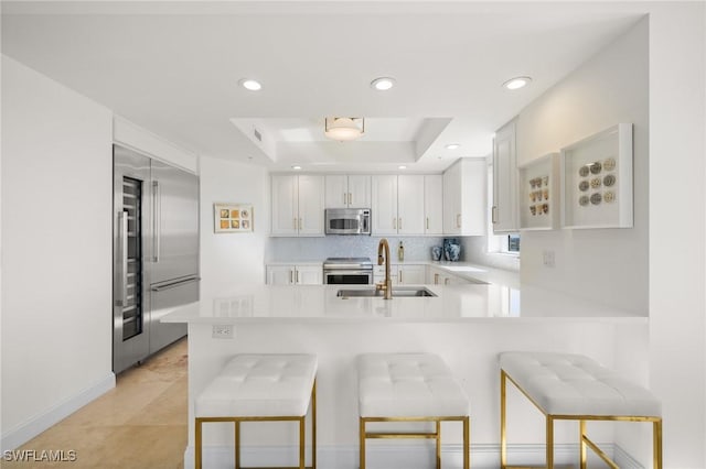 kitchen featuring a breakfast bar, appliances with stainless steel finishes, kitchen peninsula, and white cabinetry