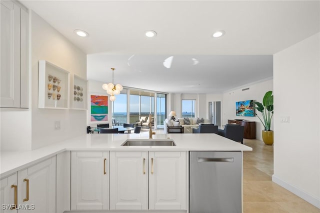 kitchen featuring kitchen peninsula, sink, stainless steel dishwasher, decorative light fixtures, and white cabinetry