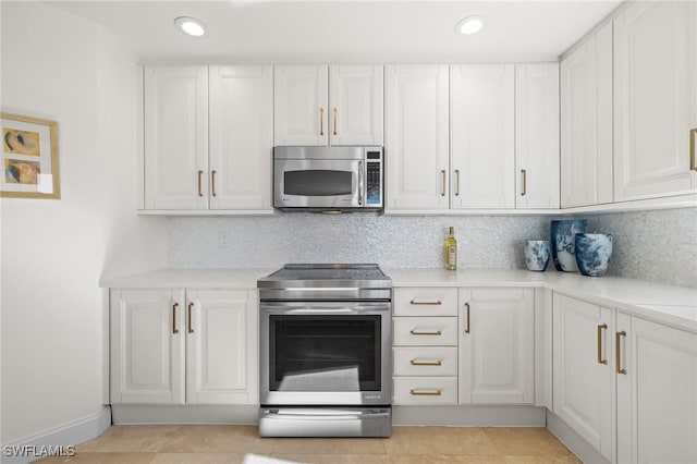 kitchen with tasteful backsplash, white cabinetry, light tile patterned floors, and appliances with stainless steel finishes