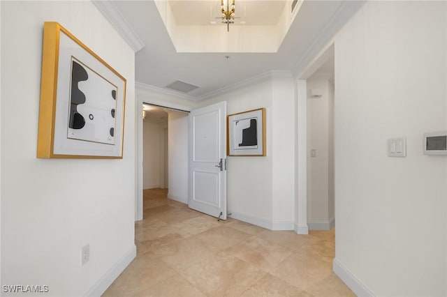 hallway with a raised ceiling, crown molding, and a chandelier