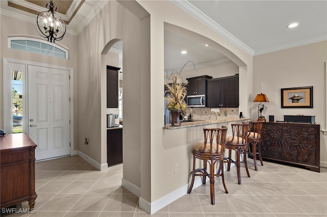 tiled foyer entrance with an inviting chandelier and ornamental molding