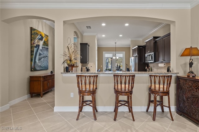 kitchen with a kitchen bar, light stone countertops, stainless steel appliances, and tasteful backsplash