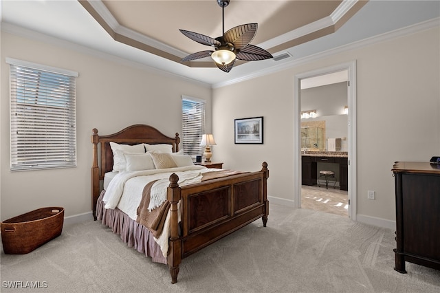 bedroom featuring ensuite bath, light colored carpet, a tray ceiling, ceiling fan, and crown molding