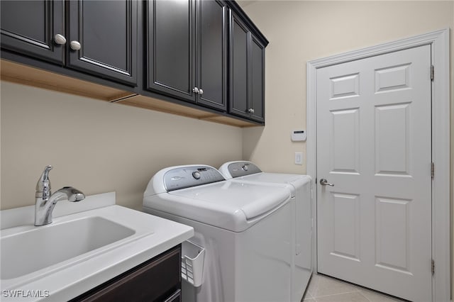 laundry room featuring cabinets, light tile patterned floors, washing machine and dryer, and sink