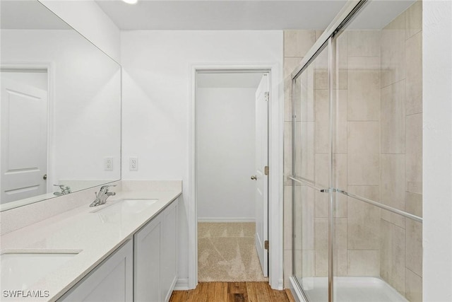 bathroom with hardwood / wood-style floors, vanity, and a shower with door