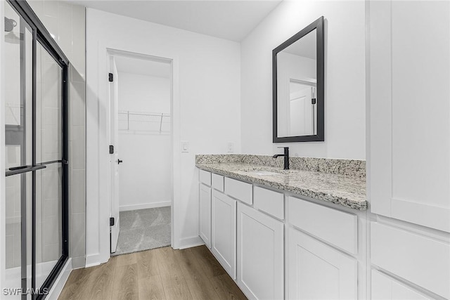 3226 NW 3rd Pl, Cape Coral, FL 33993 - bathroom with wood finished floors, a walk in closet, a stall shower, vanity, and baseboards