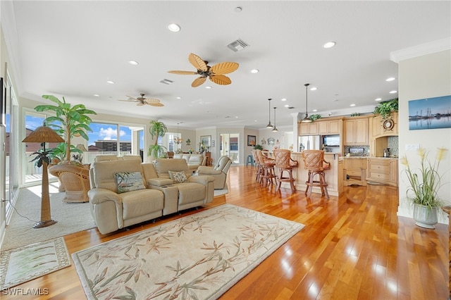 living room featuring ceiling fan, light hardwood / wood-style floors, and ornamental molding