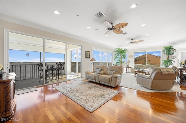 living room with hardwood / wood-style floors, ceiling fan, and ornamental molding