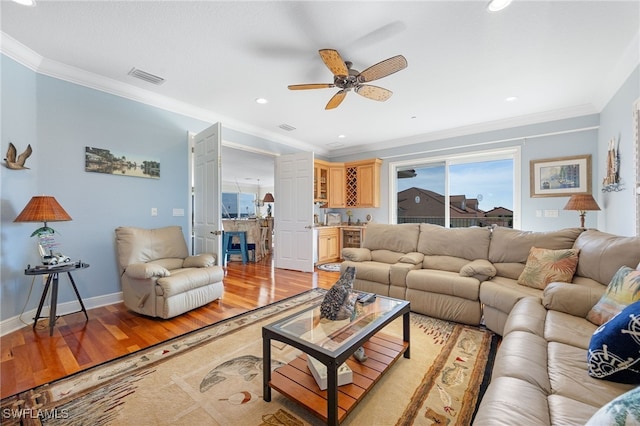 living room with light hardwood / wood-style floors, ceiling fan, and ornamental molding