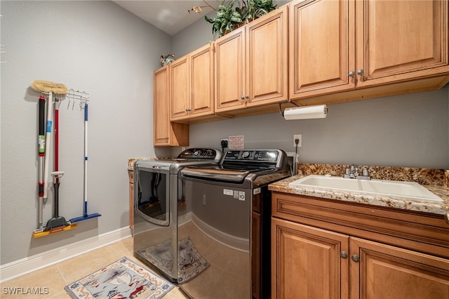 laundry area with light tile patterned flooring, cabinets, sink, and washing machine and clothes dryer