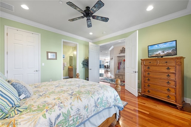 bedroom with connected bathroom, light hardwood / wood-style floors, ceiling fan, and crown molding