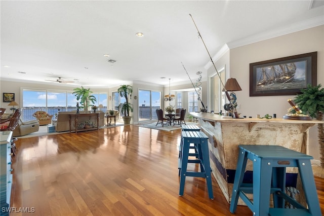 interior space featuring ceiling fan with notable chandelier, wood-type flooring, and ornamental molding