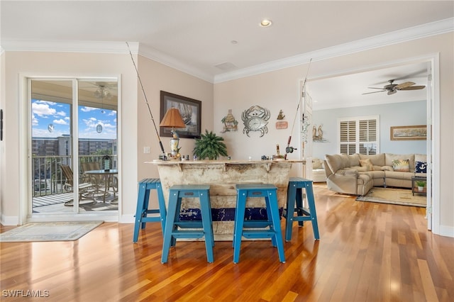 bar with wood-type flooring, ceiling fan, and crown molding