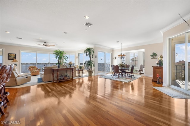 living room with crown molding, a healthy amount of sunlight, and light wood-type flooring