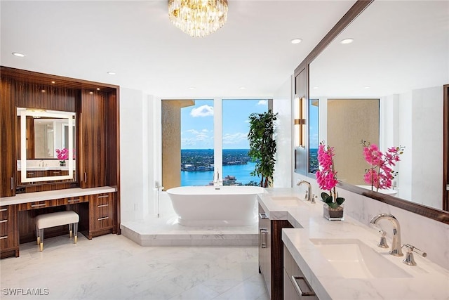 bathroom with vanity, a water view, a notable chandelier, and a tub to relax in