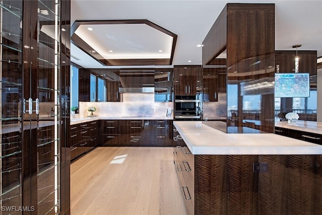 kitchen featuring backsplash, a tray ceiling, light hardwood / wood-style floors, and a center island