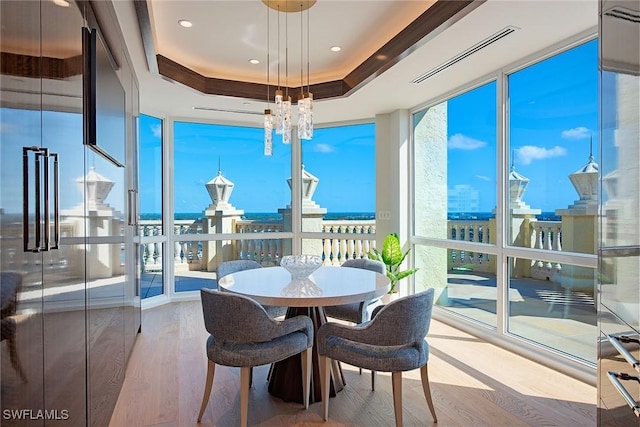 sunroom featuring a tray ceiling and a chandelier