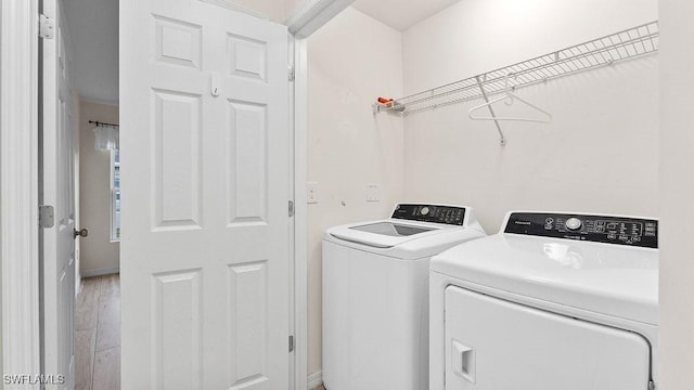 clothes washing area with washer and clothes dryer and wood-type flooring