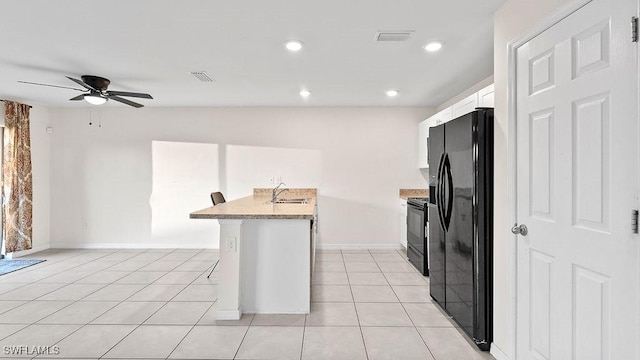 kitchen featuring ceiling fan, sink, a kitchen bar, white cabinets, and black appliances