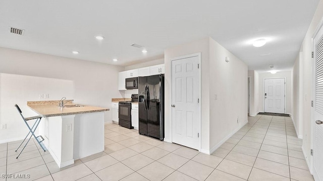 kitchen with black appliances, a kitchen breakfast bar, white cabinets, sink, and kitchen peninsula