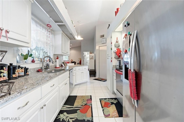 kitchen featuring sink, light stone countertops, light tile patterned floors, appliances with stainless steel finishes, and white cabinetry