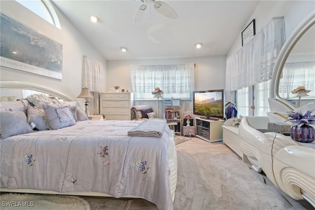 bedroom with multiple windows, light hardwood / wood-style flooring, ceiling fan, and lofted ceiling