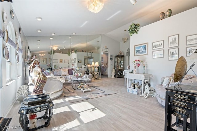 living room featuring light hardwood / wood-style floors, vaulted ceiling, and a notable chandelier