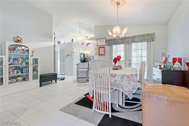 dining space featuring a chandelier, light tile patterned floors, and vaulted ceiling