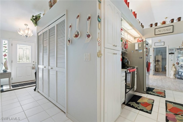 kitchen with white cabinets, light tile patterned flooring, and range