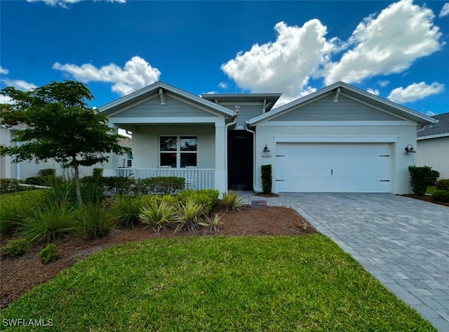 view of front of property with covered porch, a front yard, and a garage