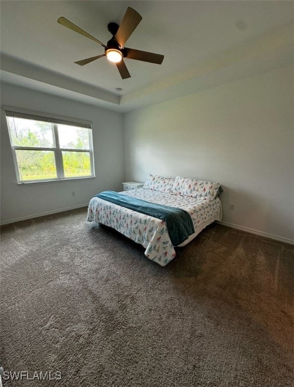 carpeted bedroom featuring a tray ceiling and ceiling fan