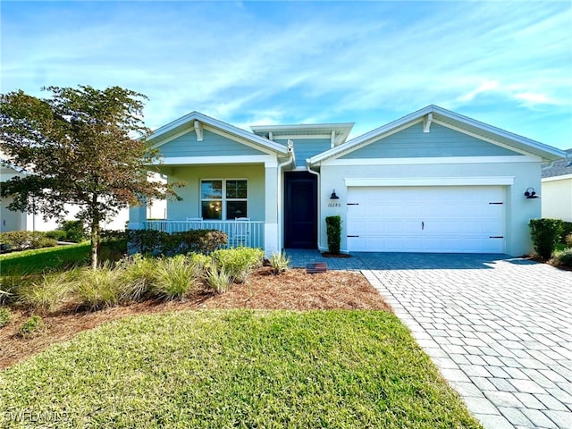 view of front of property featuring a garage, covered porch, and a front lawn