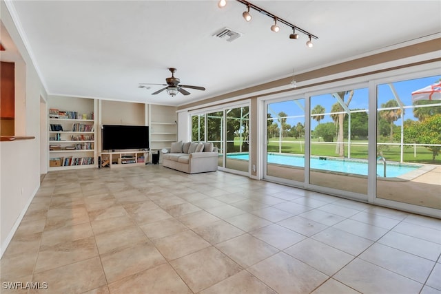 unfurnished living room with ceiling fan, built in features, ornamental molding, and light tile patterned floors