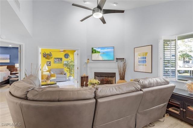 living room featuring ceiling fan, light hardwood / wood-style floors, and high vaulted ceiling