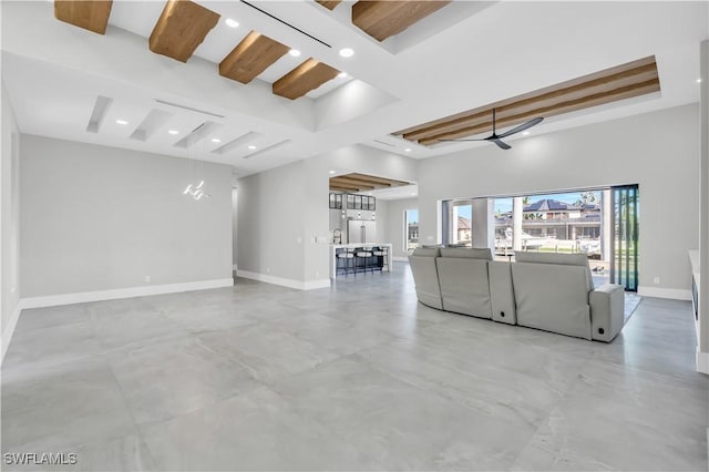 unfurnished living room featuring ceiling fan, a towering ceiling, and beam ceiling