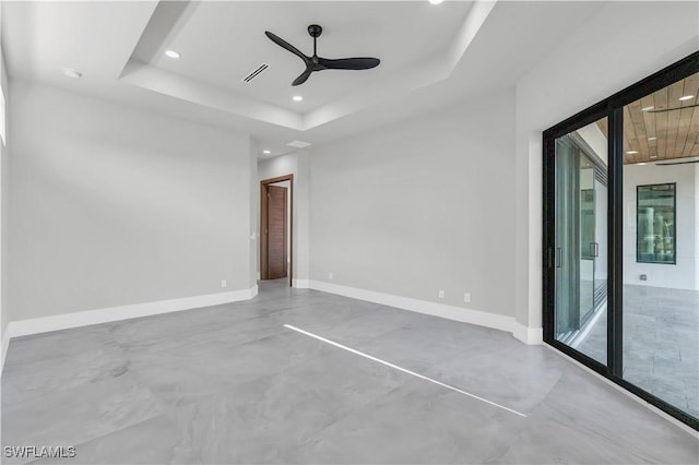 unfurnished room with concrete floors, ceiling fan, and a tray ceiling