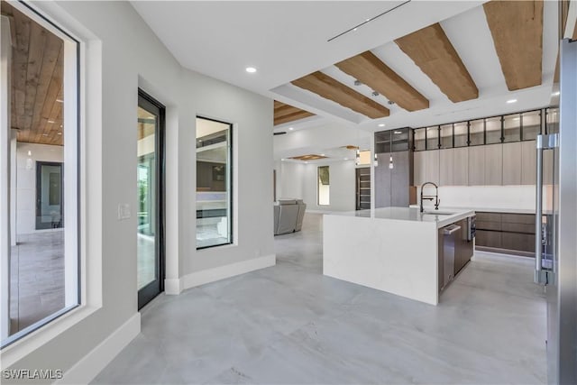 kitchen with stainless steel dishwasher, sink, a kitchen island with sink, and a wealth of natural light