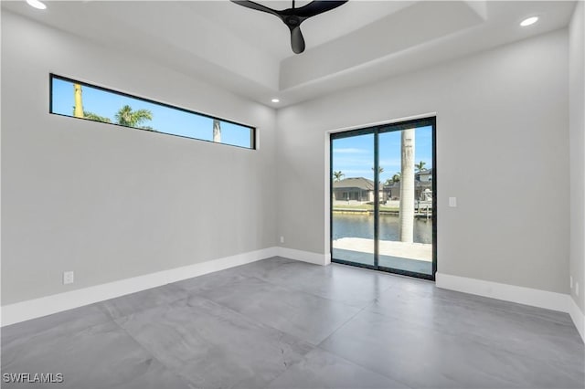 empty room featuring a water view, concrete floors, and ceiling fan