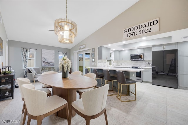 dining room featuring lofted ceiling, sink, light tile patterned floors, and a chandelier