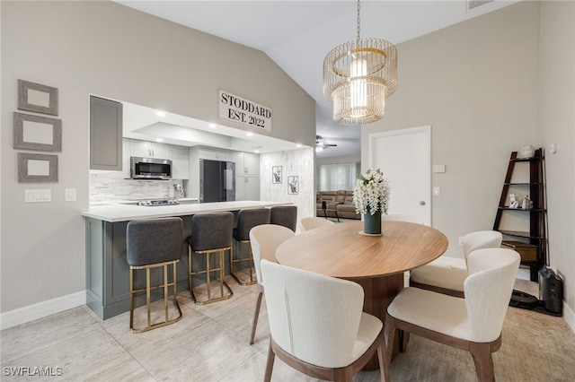 dining space with ceiling fan with notable chandelier and lofted ceiling