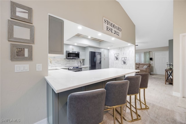 kitchen featuring gray cabinetry, a breakfast bar, sink, kitchen peninsula, and black fridge with ice dispenser