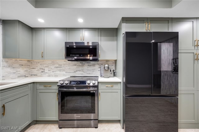 kitchen with backsplash, gray cabinetry, and appliances with stainless steel finishes