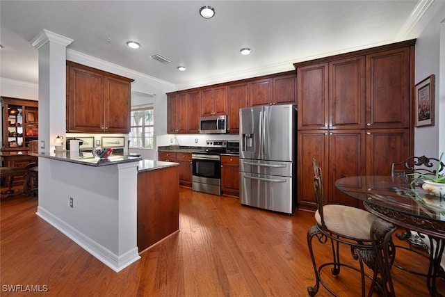 kitchen with kitchen peninsula, appliances with stainless steel finishes, light wood-type flooring, and crown molding